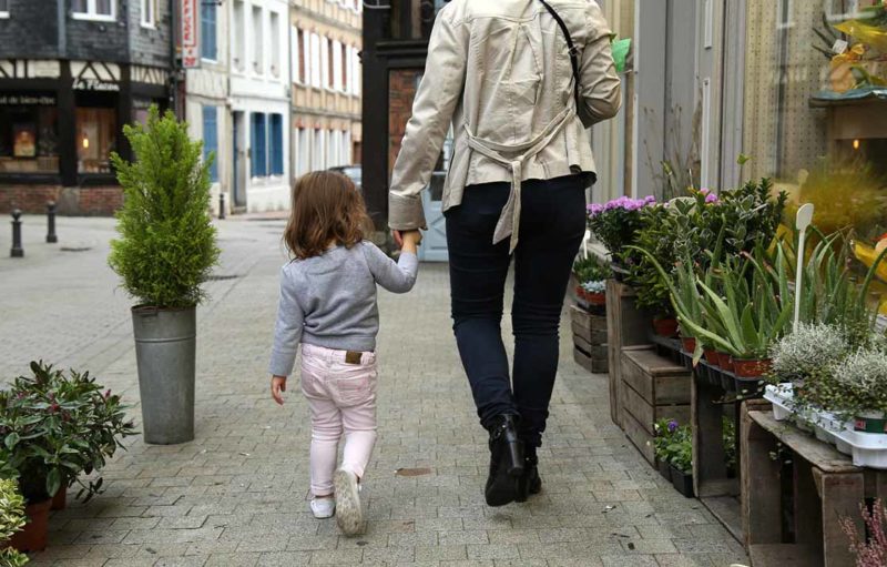 Photo représentant de dos un adulte et un enfant marchant dans une rue de Bernay