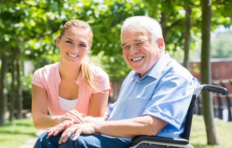 Personne âgée et femme assis sur un banc souriant