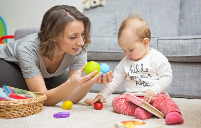 Photo évoquant du baby-sitting, représentant un bébé en train de jouer avec avec une jeune femme